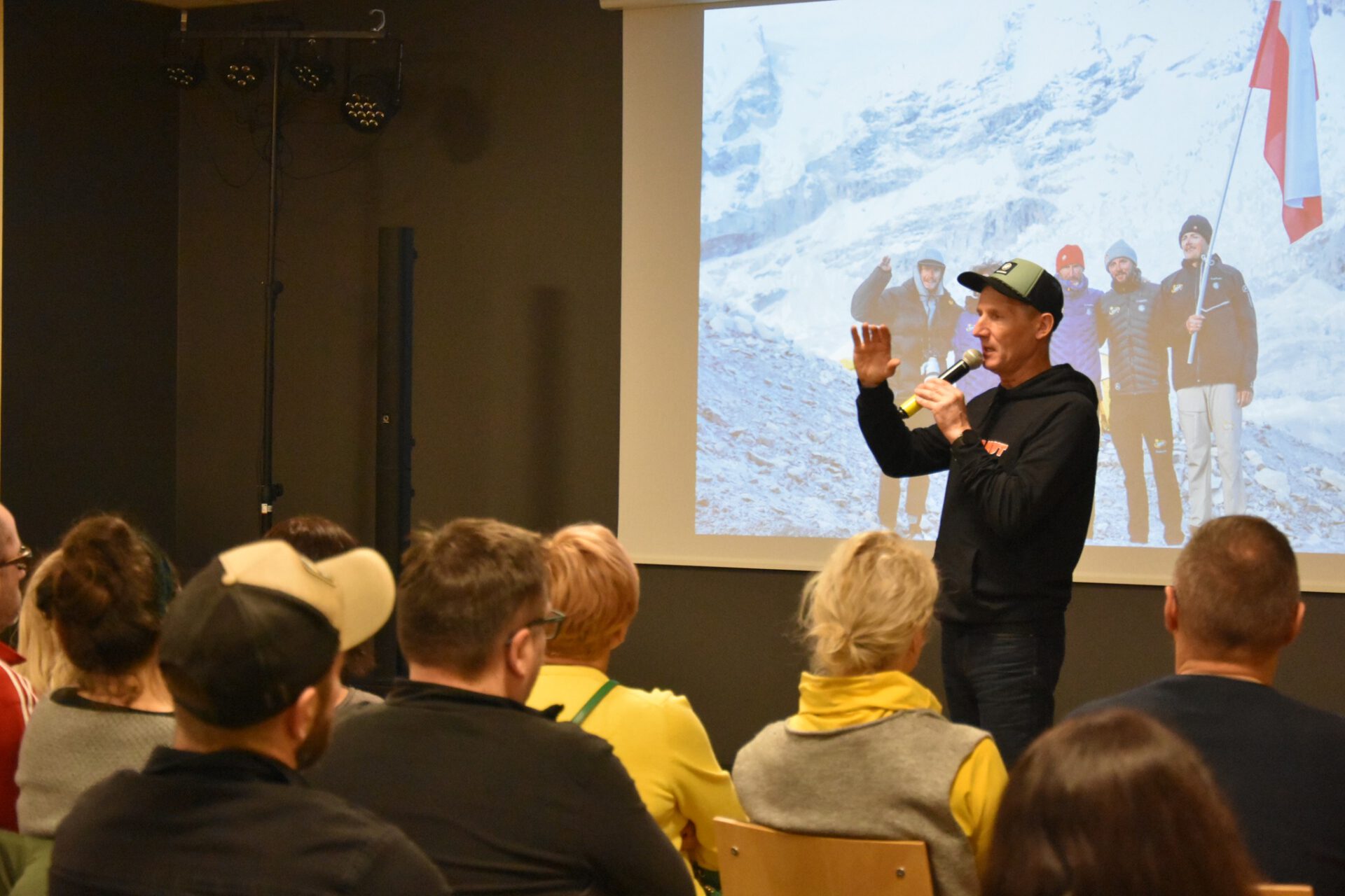 Na zdj Janusz Gołąb na tle slajdu z Himalaj ów , na którym widoczna jest ekipa Everest SKi i Polska flaga