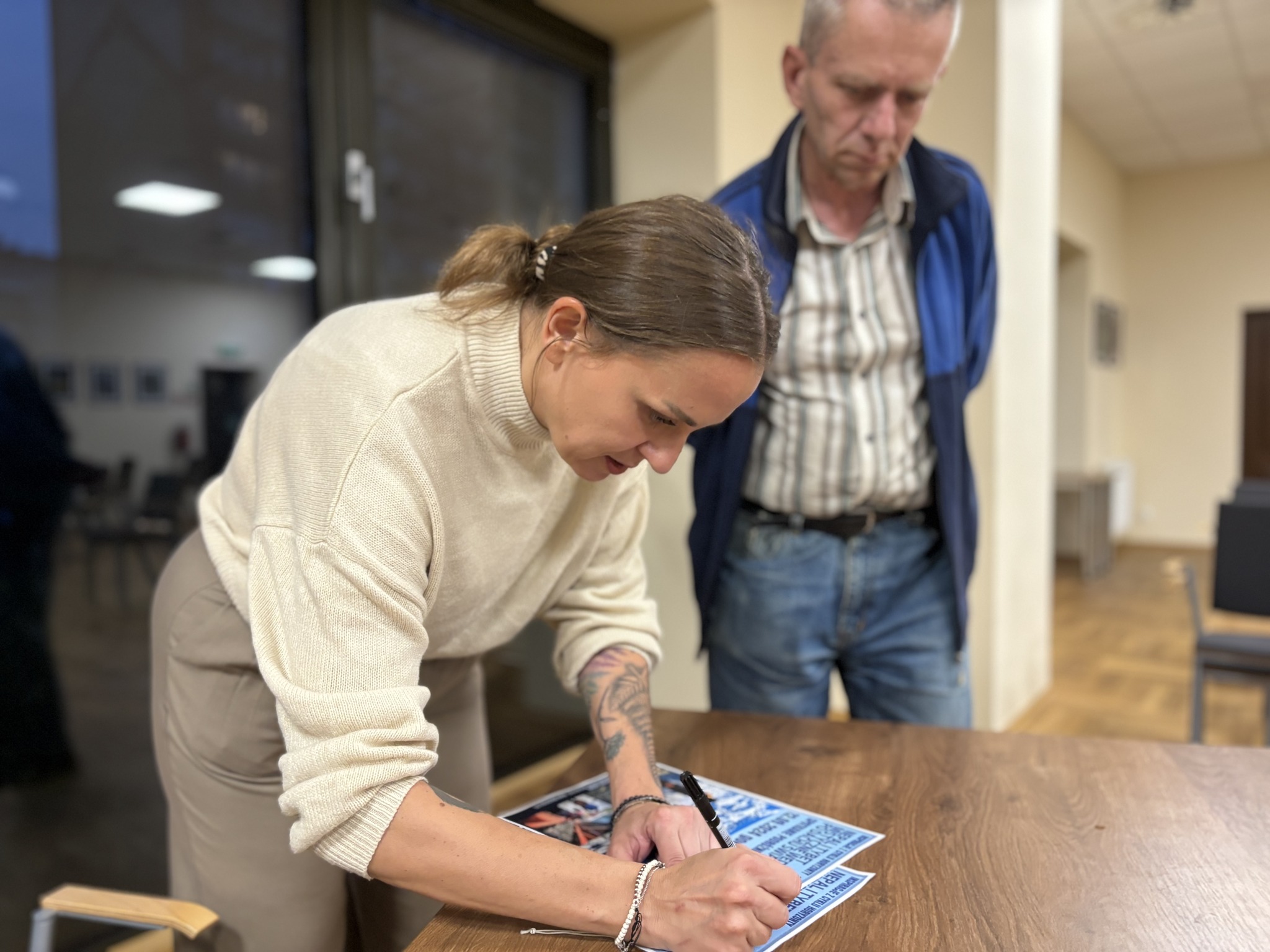 Alicja Żak podpisuje plakat ze spotkania