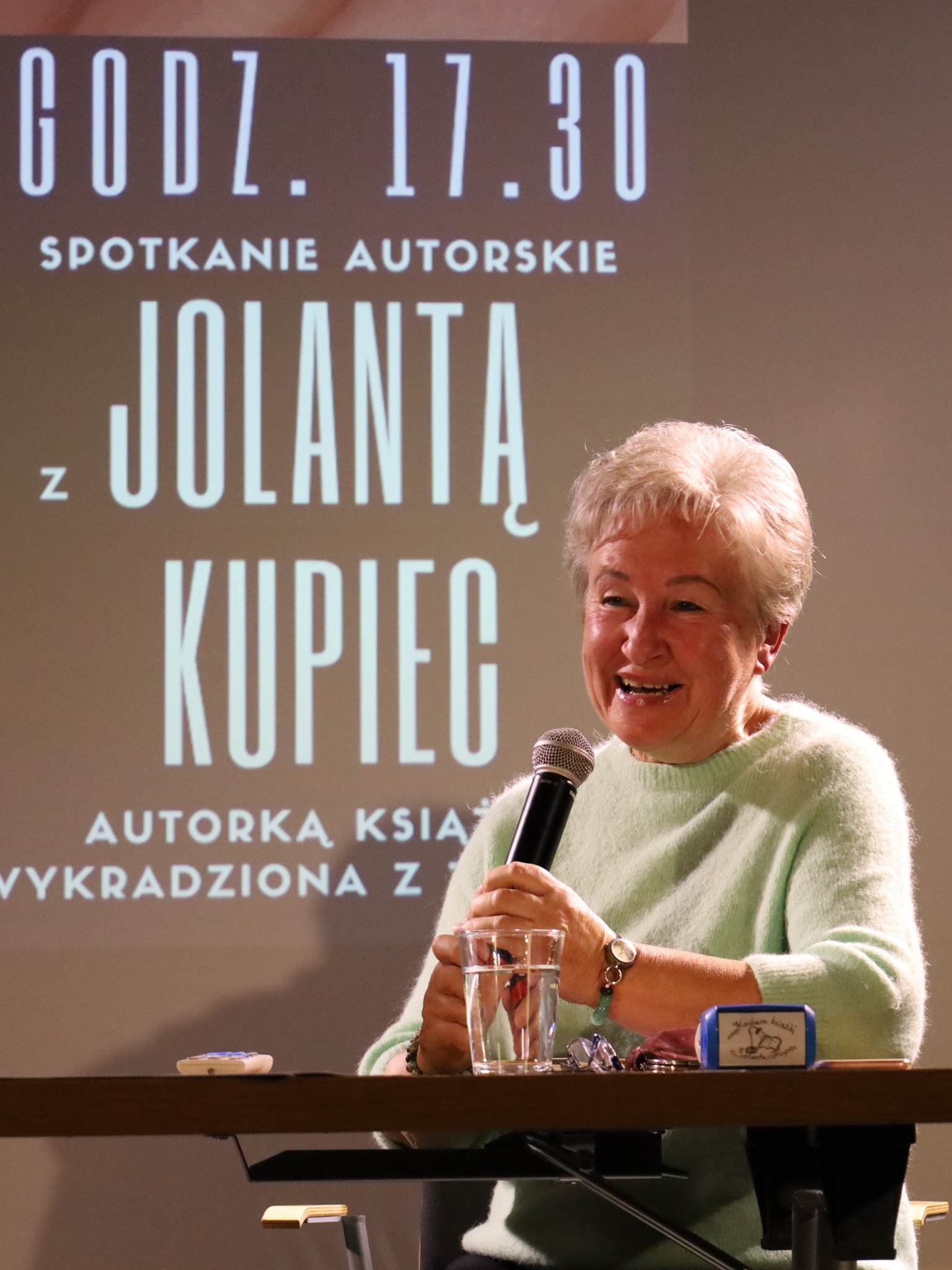 Jolanta Kupiec na rozpoczęciu spotkania na tle ekranu